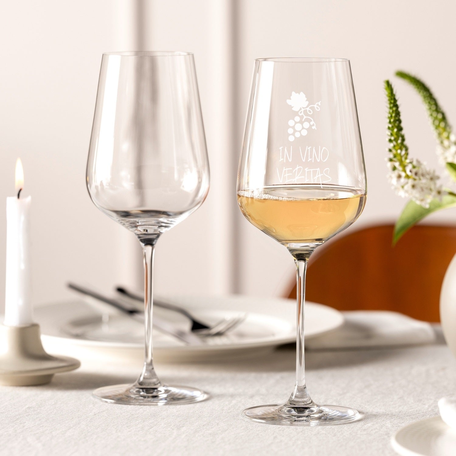 Zwei Weißweingläser BRUNELLI auf gedecktem Tisch, eines mit Gravur und Weißwein gefüllt