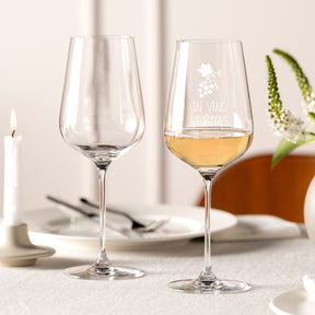 Zwei Weißweingläser BRUNELLI auf gedecktem Tisch, eines mit Gravur und Weißwein gefüllt