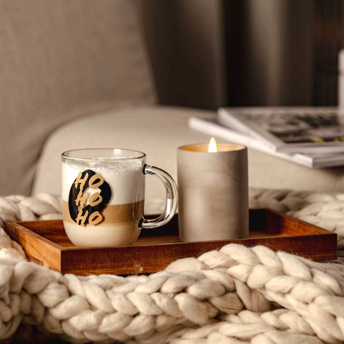 Tasse SILENZIO mit HO HO HO-Gravur auf Holztablett neben Kerze