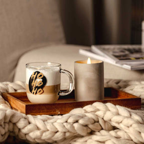 Tasse SILENZIO mit HO HO HO-Gravur auf Holztablett neben Kerze
