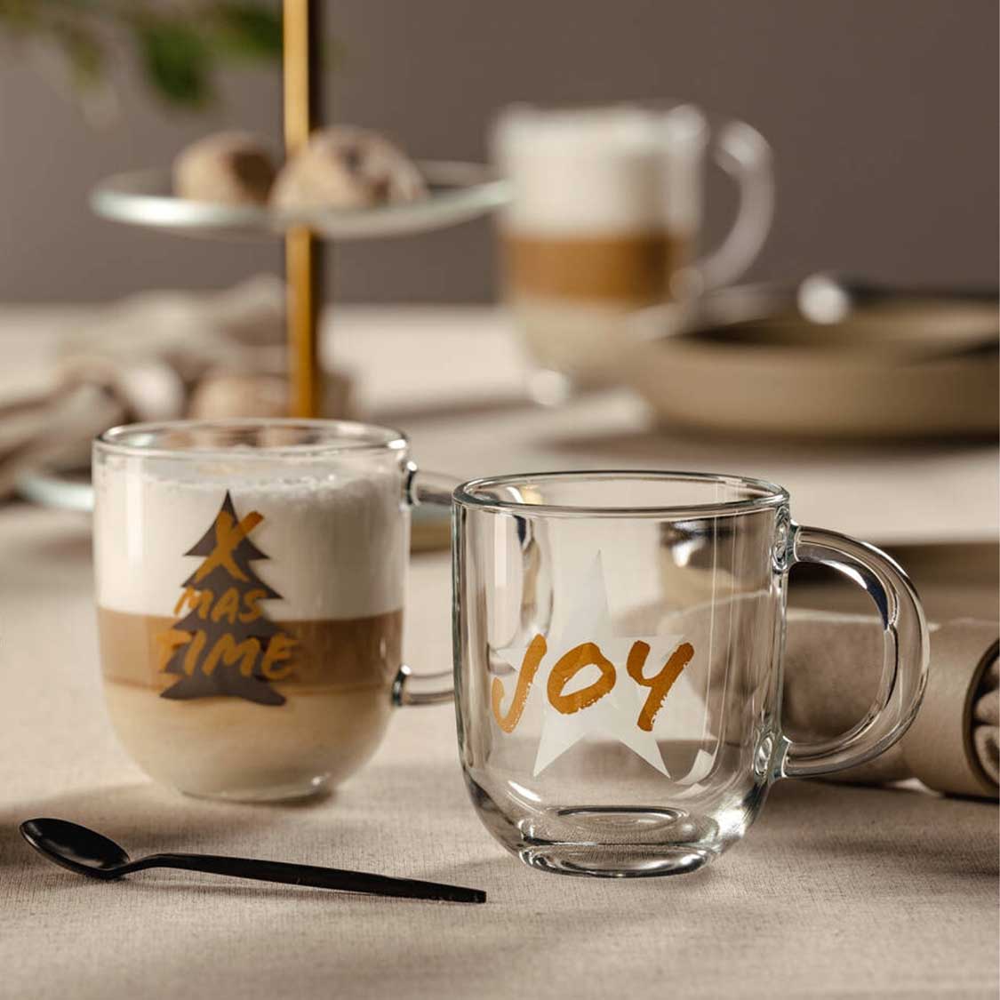 Glastasse SILENZIO mit goldfarbener Gravur JOY auf gedecktem Tisch