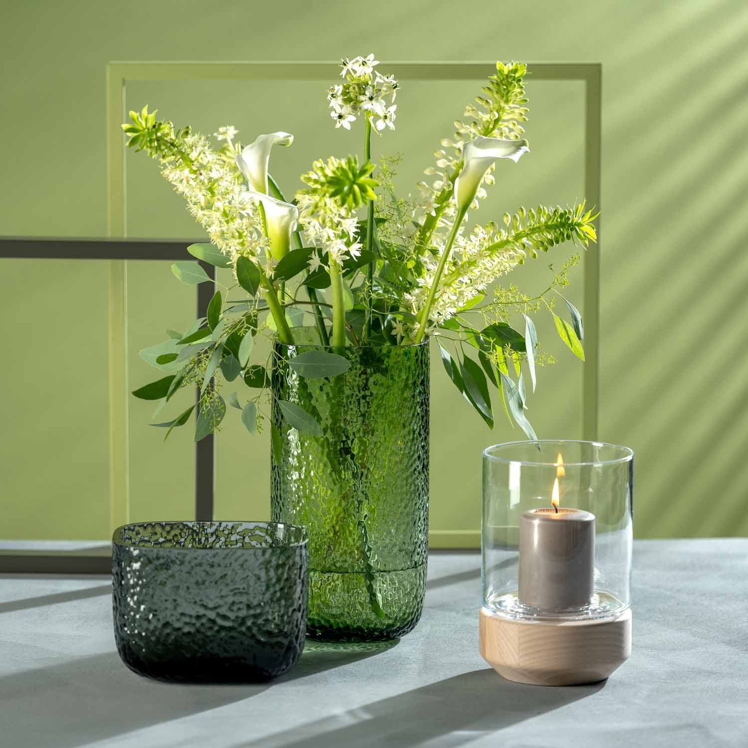 Vase MARTELLO 29 cm grün mit Blumenstrauß auf Tisch, daneben Kerze
