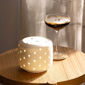 LED Laterne LAGO mit weißem Punktmuster auf Holztisch, Cocktailglas im Hintergrund