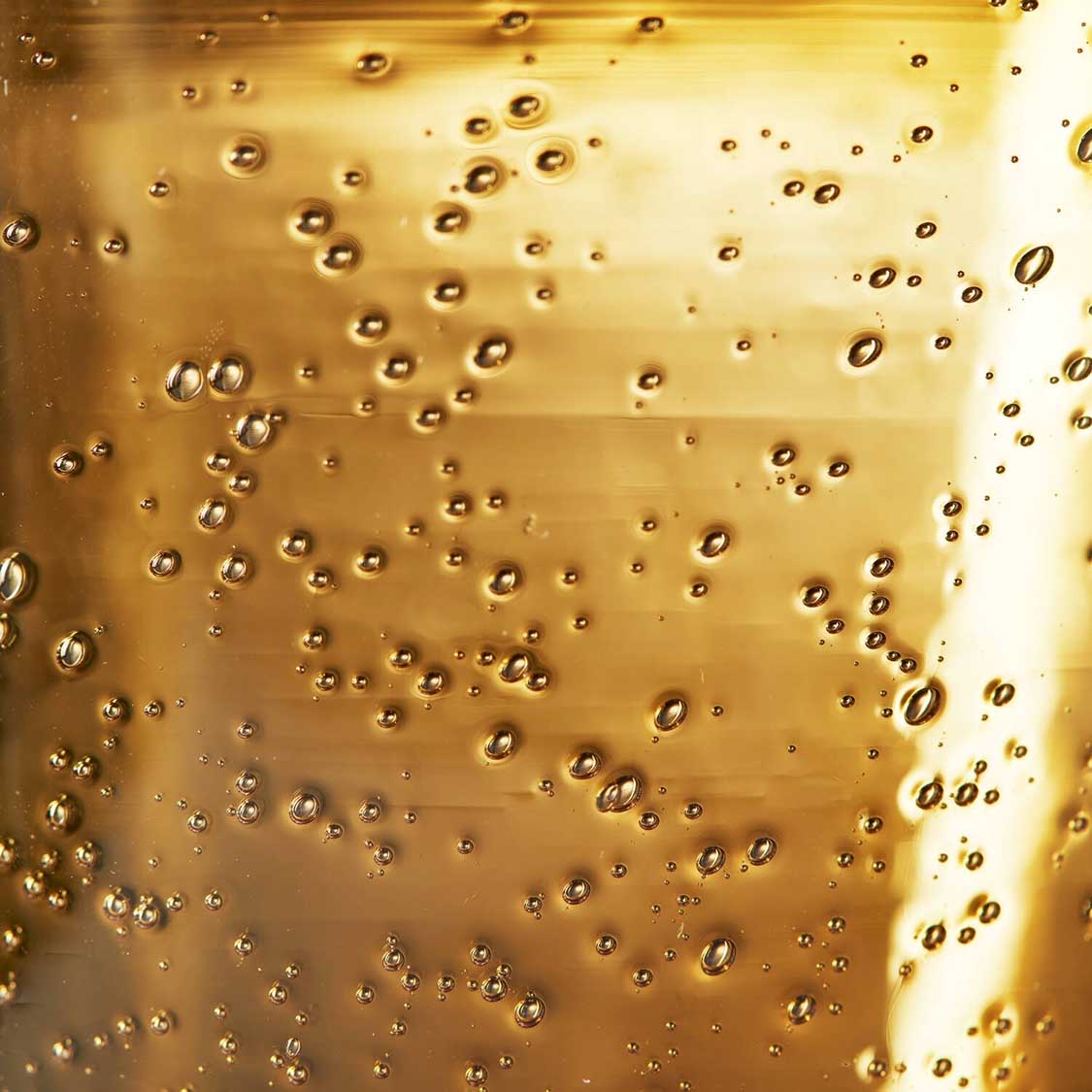 Bernsteinfarbenes Glas mit Blasen und Lichtbrechung gefüllt