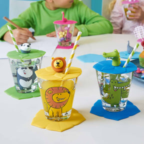 Kindertrinksets mit Tiermotiven und farbigen Deckeln auf Kindertisch, Kind im grünen Shirt