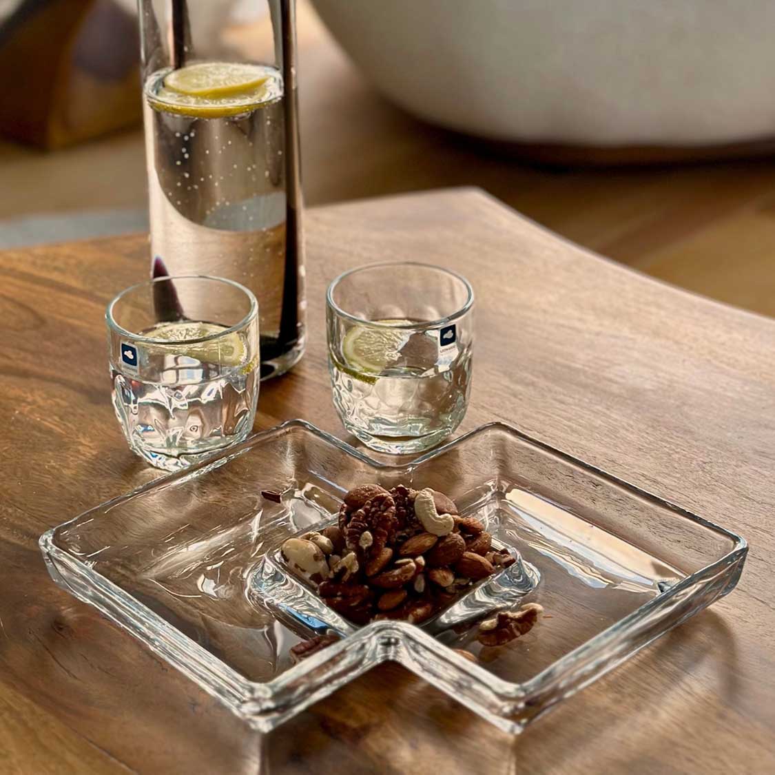 Kabarett SEZIONE auf Holztisch mit Nüssen, Wassergläsern und Flasche