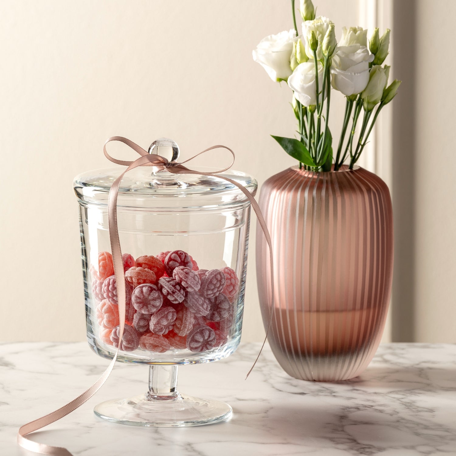 Vase BELLAGIO mit weißen Blüten, daneben Glas mit roten Himbeeren auf Marmortisch
