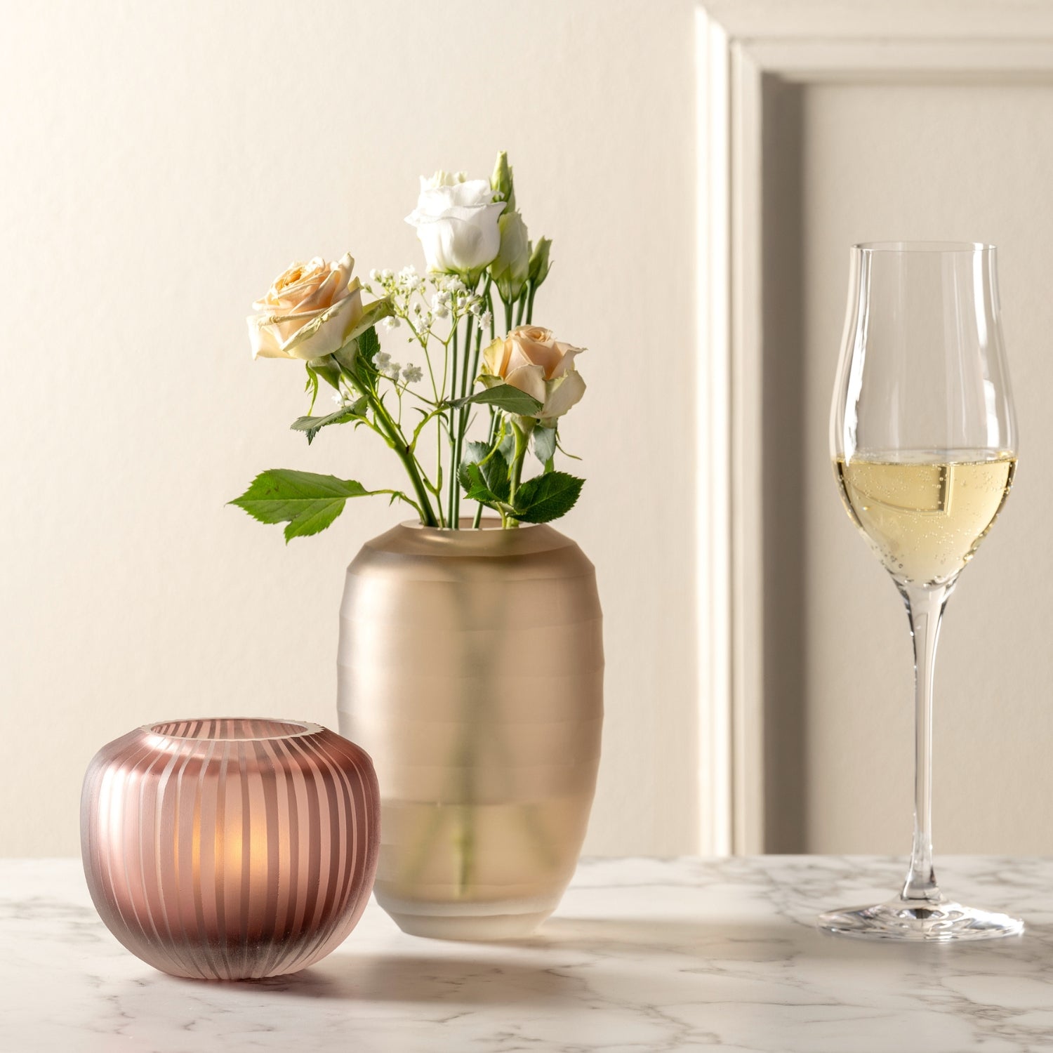 Vase BELLAGIO mit Blumen auf Marmortisch, daneben Weinglas und rote Kerze