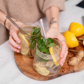 Zwei Trinkgläser SANO mit Mojito, Minze und Zitrone in Händen