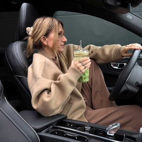 Frau im Auto hält ToGo Becher SANO 500 ml vanilla während der Fahrt