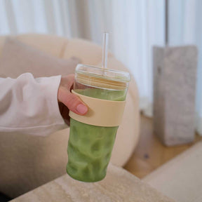 Person hält ToGo Becher SANO mit grünem Getränk und Strohhalm