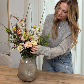 Vase HAZEL 25 cm beige mit Frühjahrsblumen gefüllt, von Frau gehalten