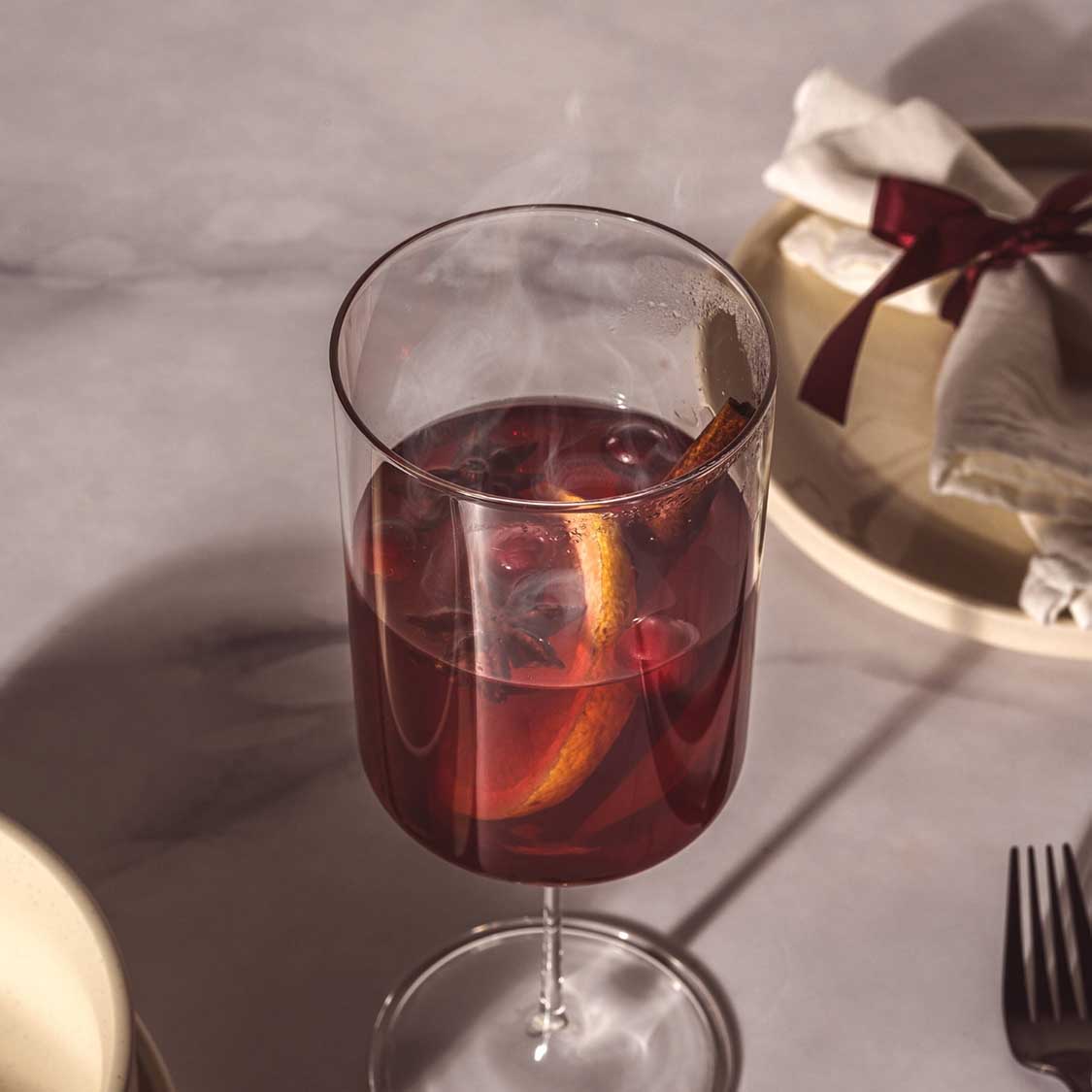 Kelchglas BASSO mit rotem Getränk und Eiswürfeln, gedeckter Tisch