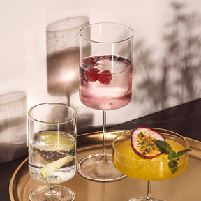 Kelchgläser mit Cocktails und Getränken auf goldenem Tablett