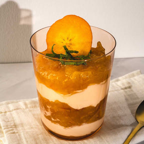 Trinkglas LEGGERO mit geschichtetem Dessert und Orange als Garnitur auf Tisch
