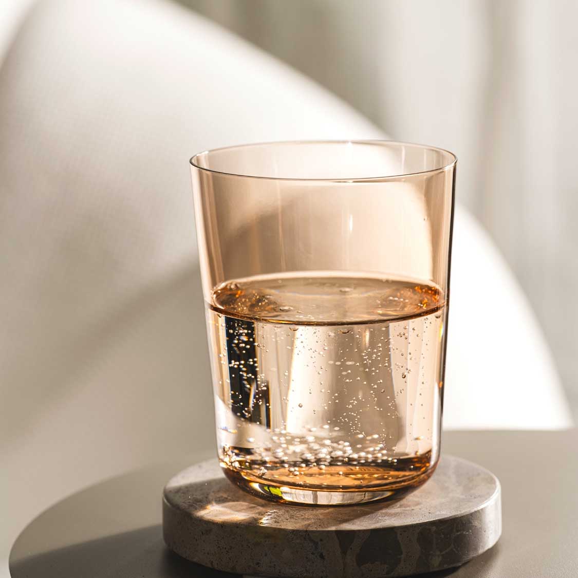 Trinkglas LEGGERO mit Wasser und Eiswürfeln auf Steinuntersetzer, Sonnenlicht