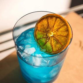 Trinkglas LEGGERO mit blauem Cocktail, Eiswürfeln, Orangenscheibe und Minze gefüllt