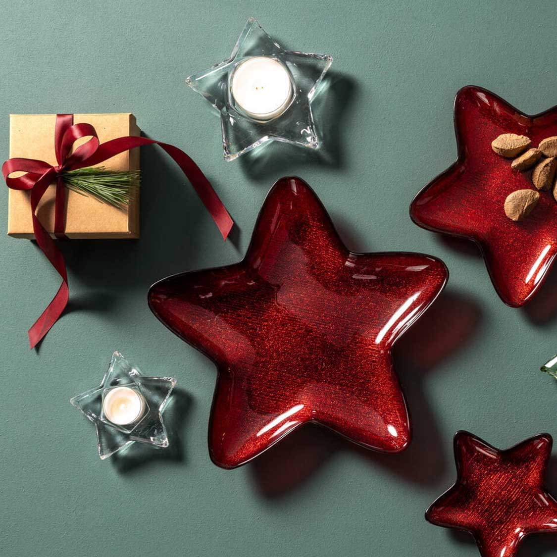Rote Glassterne mit Teelichtern, Geschenkbox und grauem Hintergrund in Weihnachtsdeko