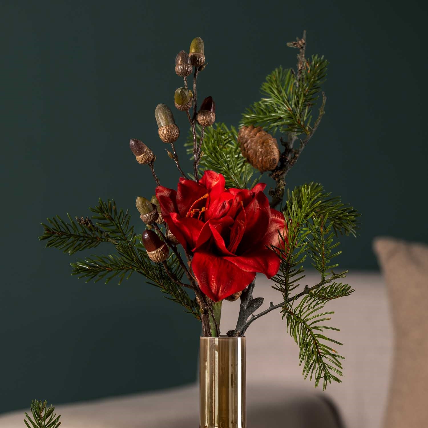 Rote Blume mit Pinienzweig in Glasvase vor grauem Hintergrund