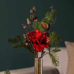 Rote Blume mit Pinienzweig in Glasvase vor grauem Hintergrund