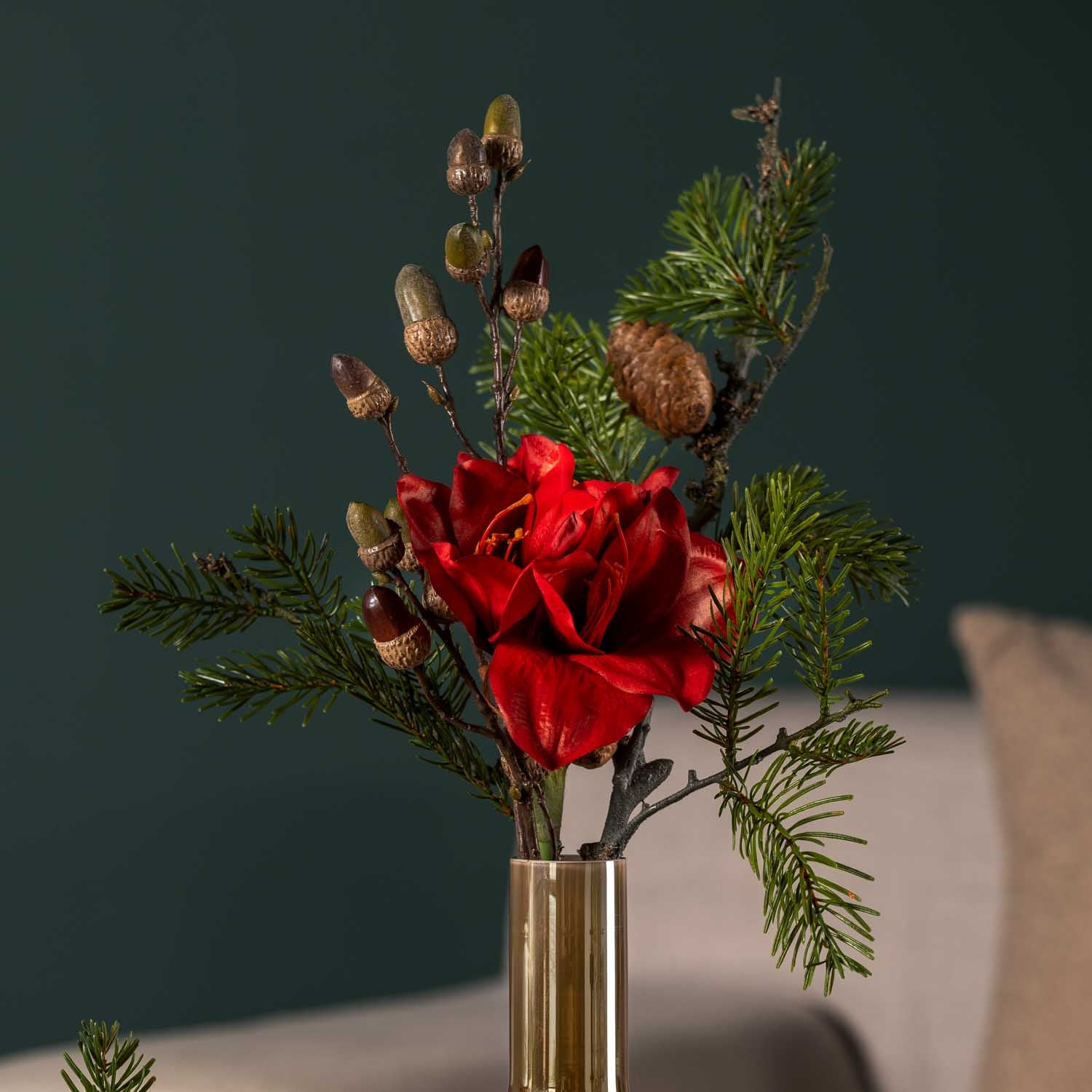 Rote Amaryllis in Glasvase vor grauem Hintergrund mit Grünwerk
