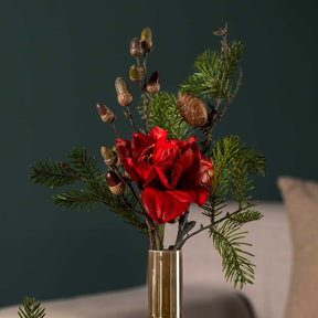 Rote Amaryllis in Glasvase vor grauem Hintergrund mit Grünwerk