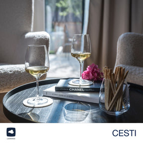 Rieslinggläser CESTI auf gedecktem Tisch mit Weißwein, Büchern und Deko