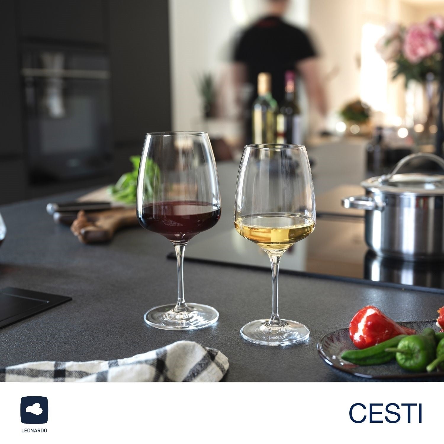 Weißweinglas CESTI und Rotwein­glas auf gedecktem Küchen­tisch mit Gemüse