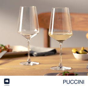 Zwei Weißweingläser PUCCINI auf Holztisch, eines leer, eines gefüllt