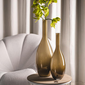 Vase BEAUTY in Braun mit Grünpflanzen im Wohnzimmer neben weißem Sessel