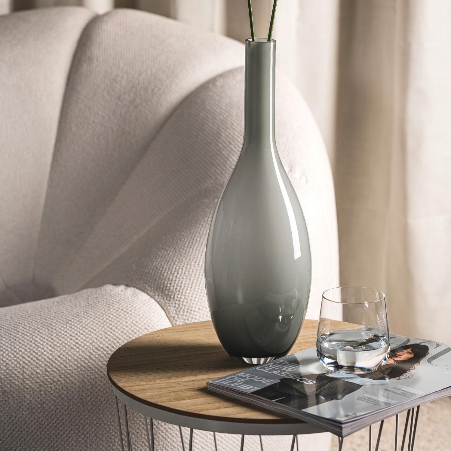 Vase BEAUTY grau auf Beistelltisch neben Sessel im Wohnzimmer