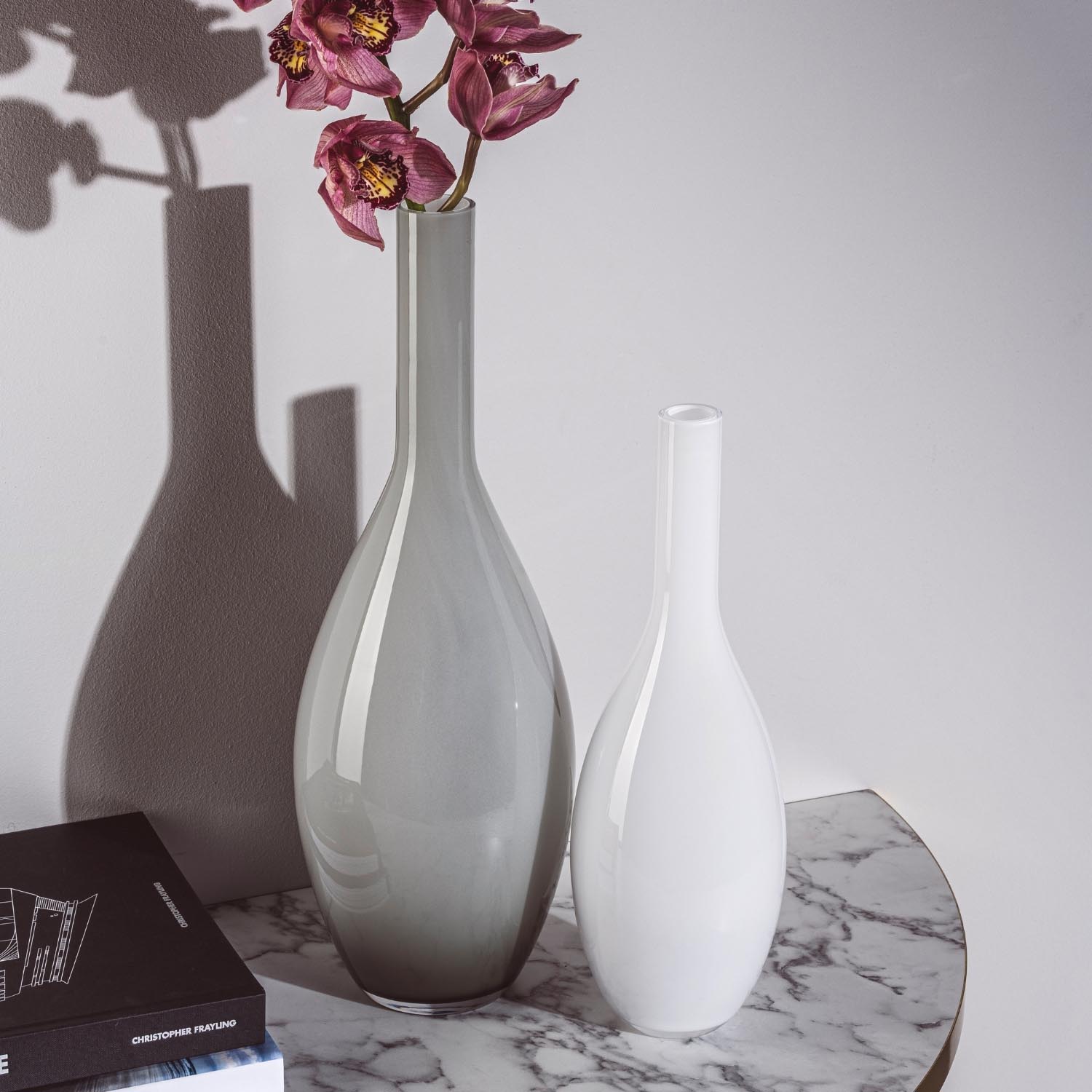 Vase BEAUTY 50 cm grau mit roten Blüten auf Marmortisch neben weißer Vase