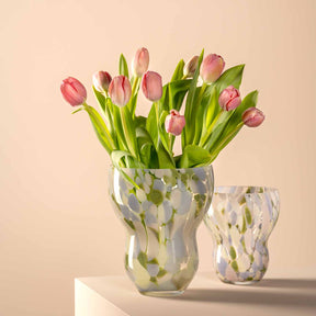 Vase VIVACE mit rosa Tulpen und grünen Blättern, daneben kleinere Vase, auf beigem Hintergrund
