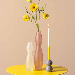Vase VIVACE 25 cm satiniert mit gelben Blumen auf gelbem Tisch, Kerze daneben
