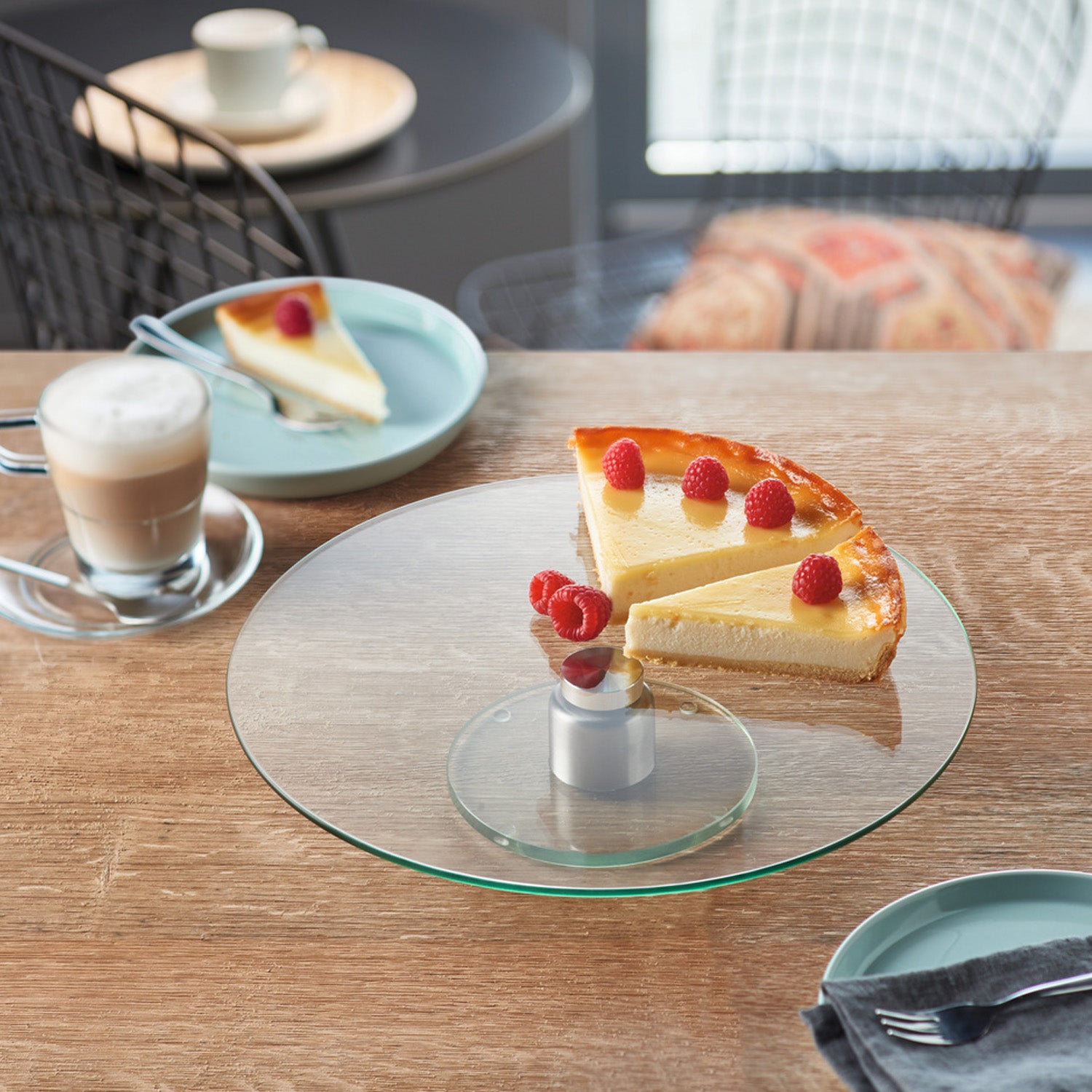 Tortenplatte TURN mit Käsekuchen und Himbeeren auf gedecktem Tisch, daneben Kaffee