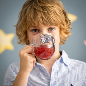Kind hält Tasse BAMBINI AVVENTURA mit Weltall-Motiv vor Gesicht