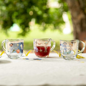 Drei Glasbecher mit Weltall-Motiven auf Tisch im Freien, einer mit roter Flüssigkeit gefüllt
