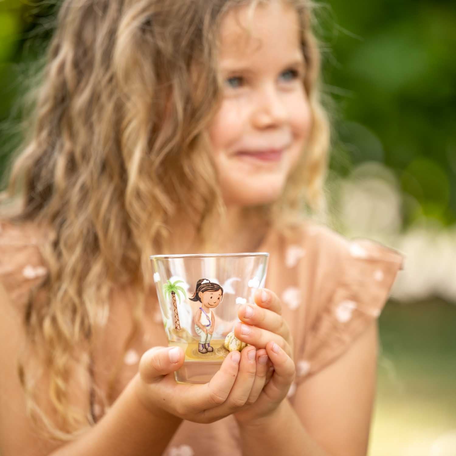 Maedchen haelt Trinkglas BAMBINI AVVENTURA mit Dino-Motiv im Freien