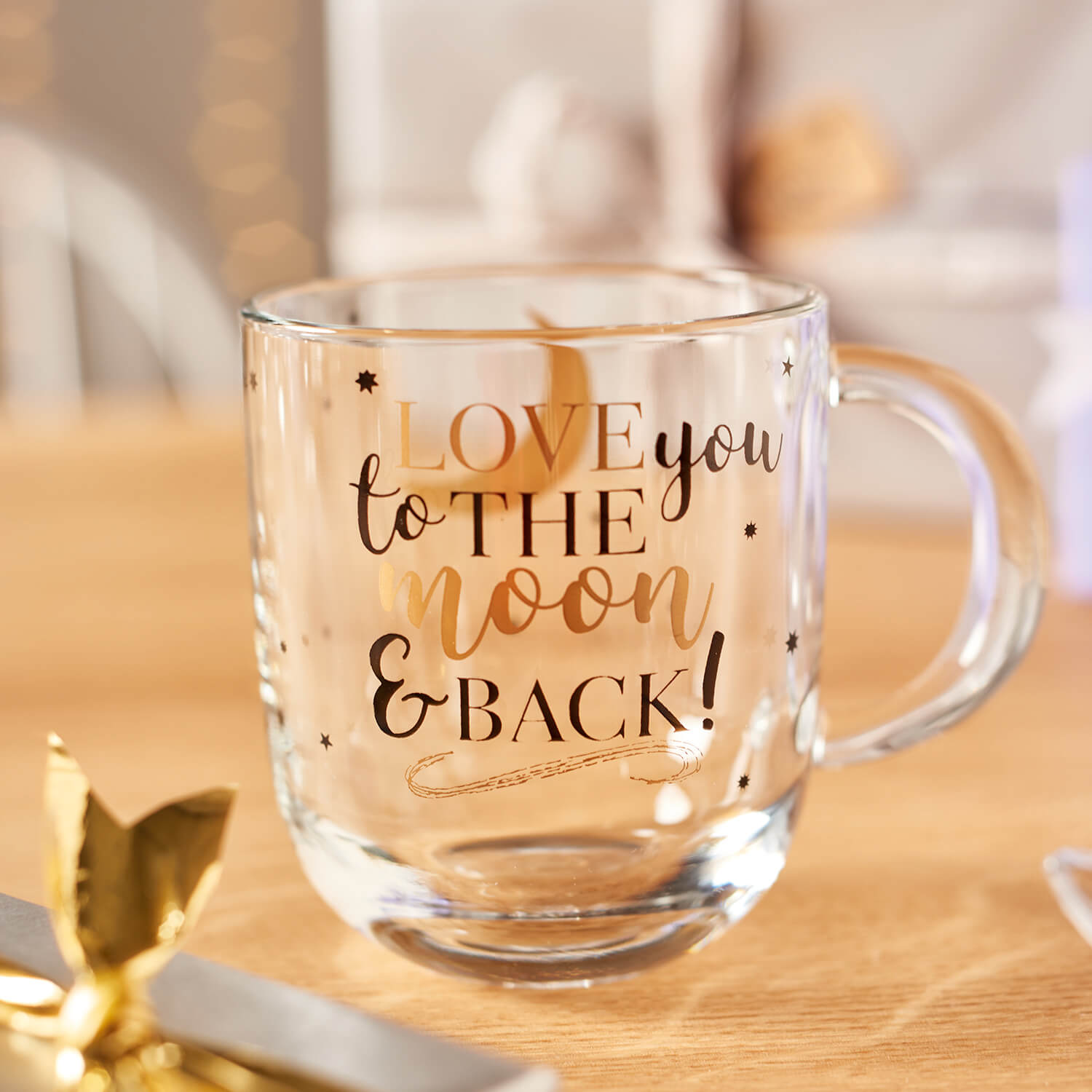 Glastasse EMOZIONE mit Gravur "Love you to the moon and back", auf Holztisch mit Dekoration