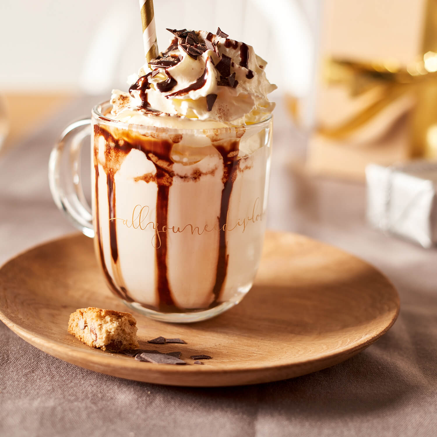 Tasse EMOZIONE mit Kakaogetränk, Schlagsahne, Schokoladenbrösel auf Holzuntersetzer, Goldschrift