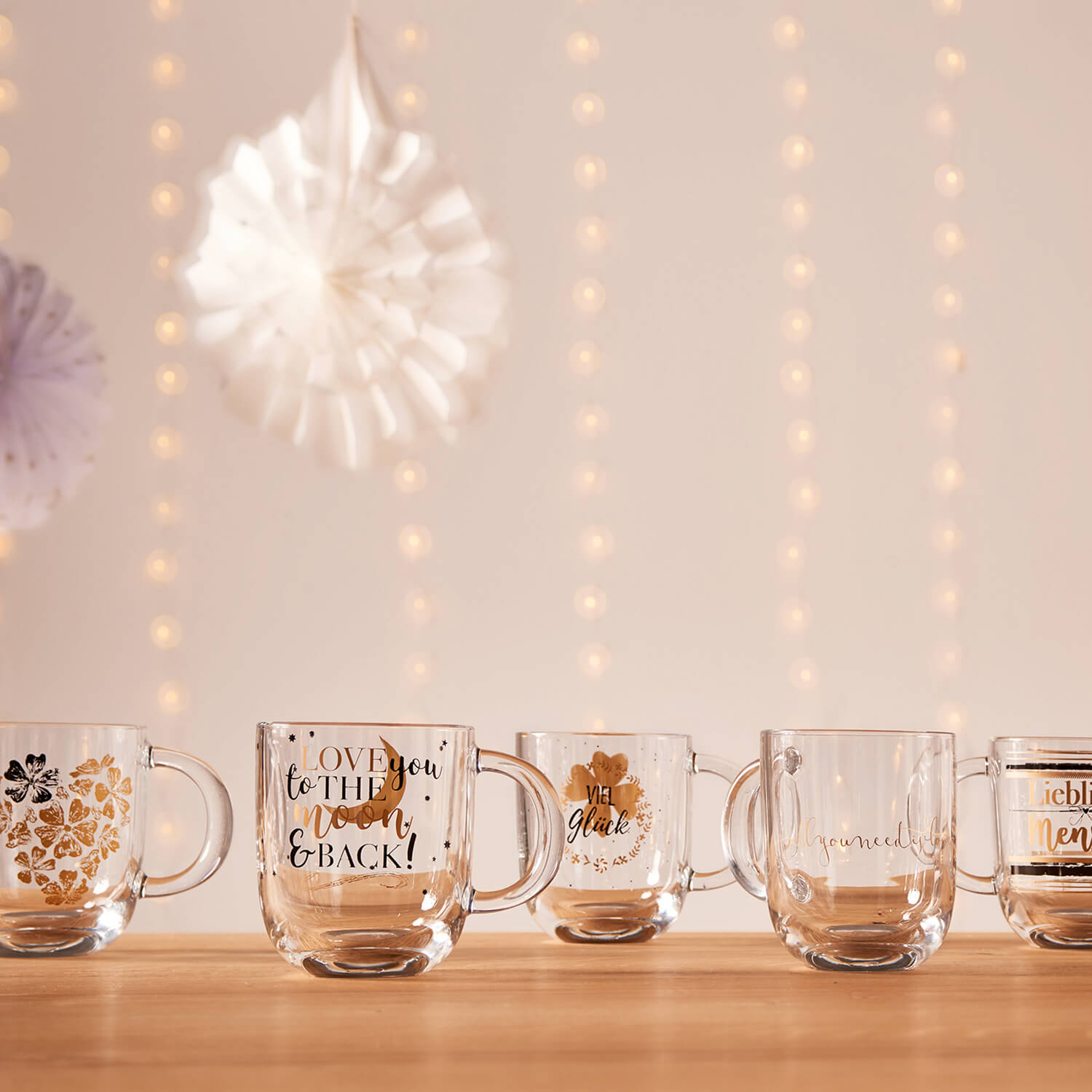 Mehrere Glastassen mit verschiedenen Motiven auf Holztisch, dekorativ arrangiert