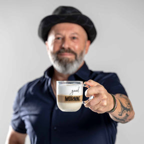 Mann mit Bart und schwarzem Hut hält Glastasse UFFICIO 400 ml 'good MORNING