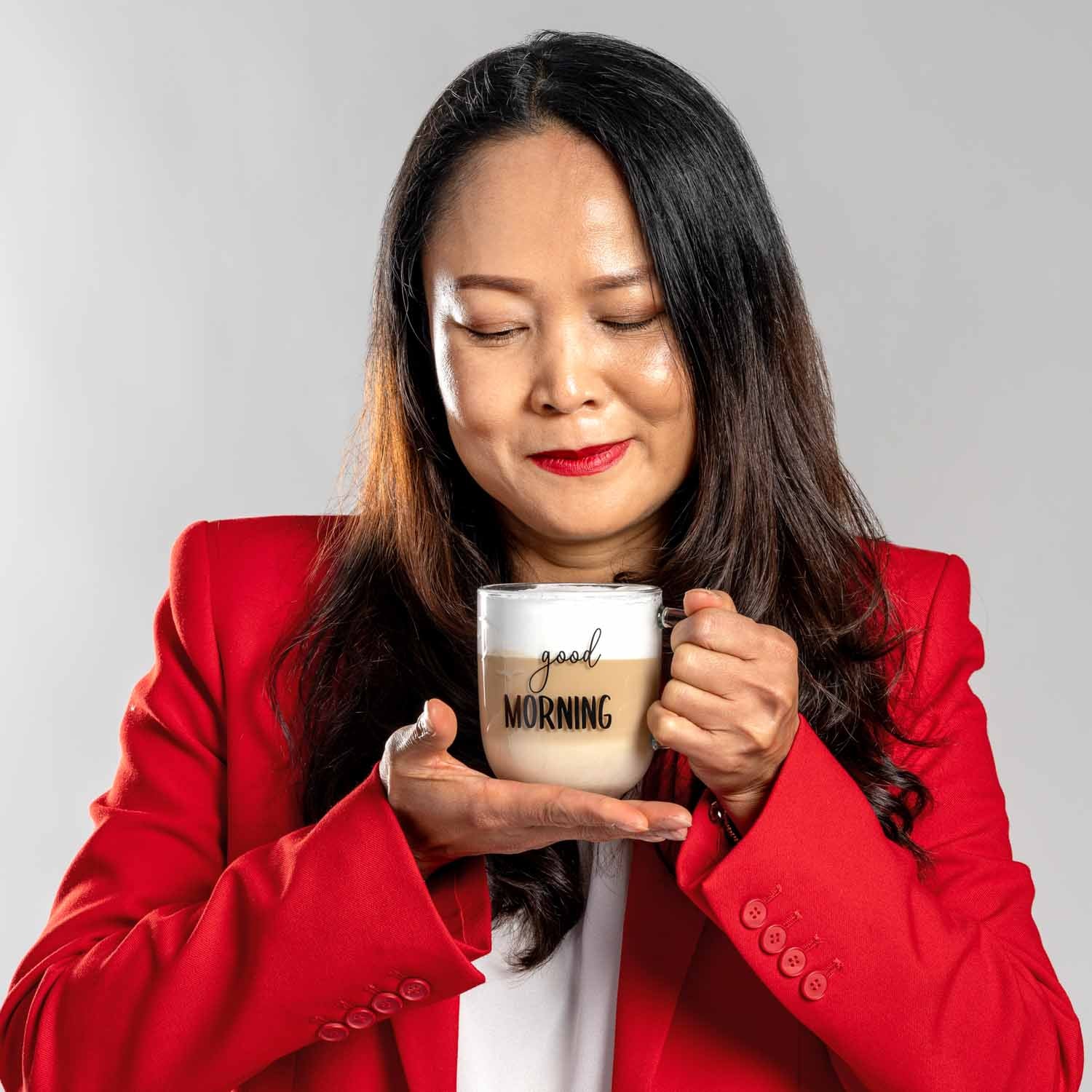 Frau in rotem Blazer hält Glastasse UFFICIO mit "good MORNING" Gravur