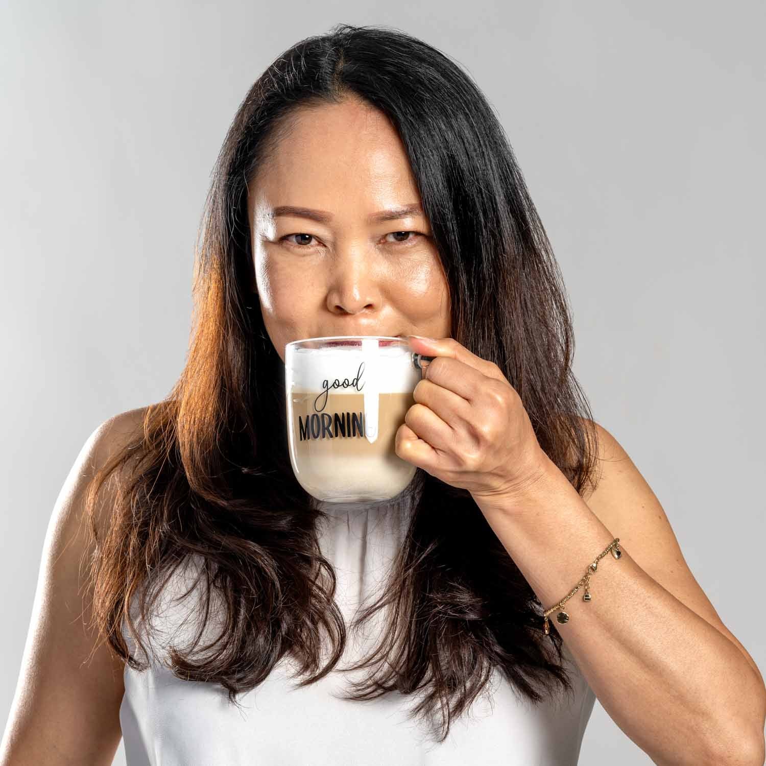 Frau trinkt aus Glastasse UFFICIO mit 'good MORNING' Gravur