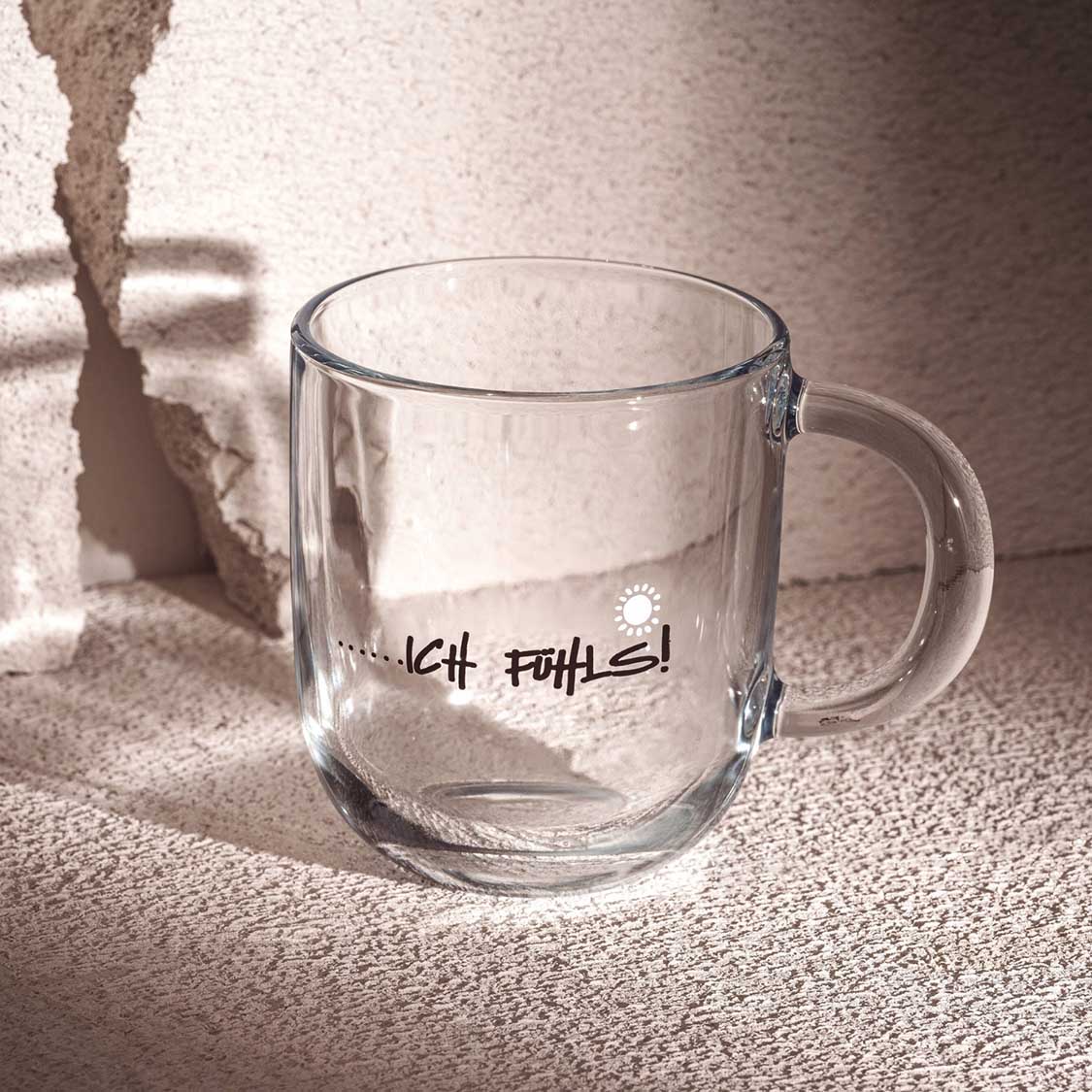 Glastasse EMOZIONE mit Gravur "…ich fühls!" auf heller Oberfläche