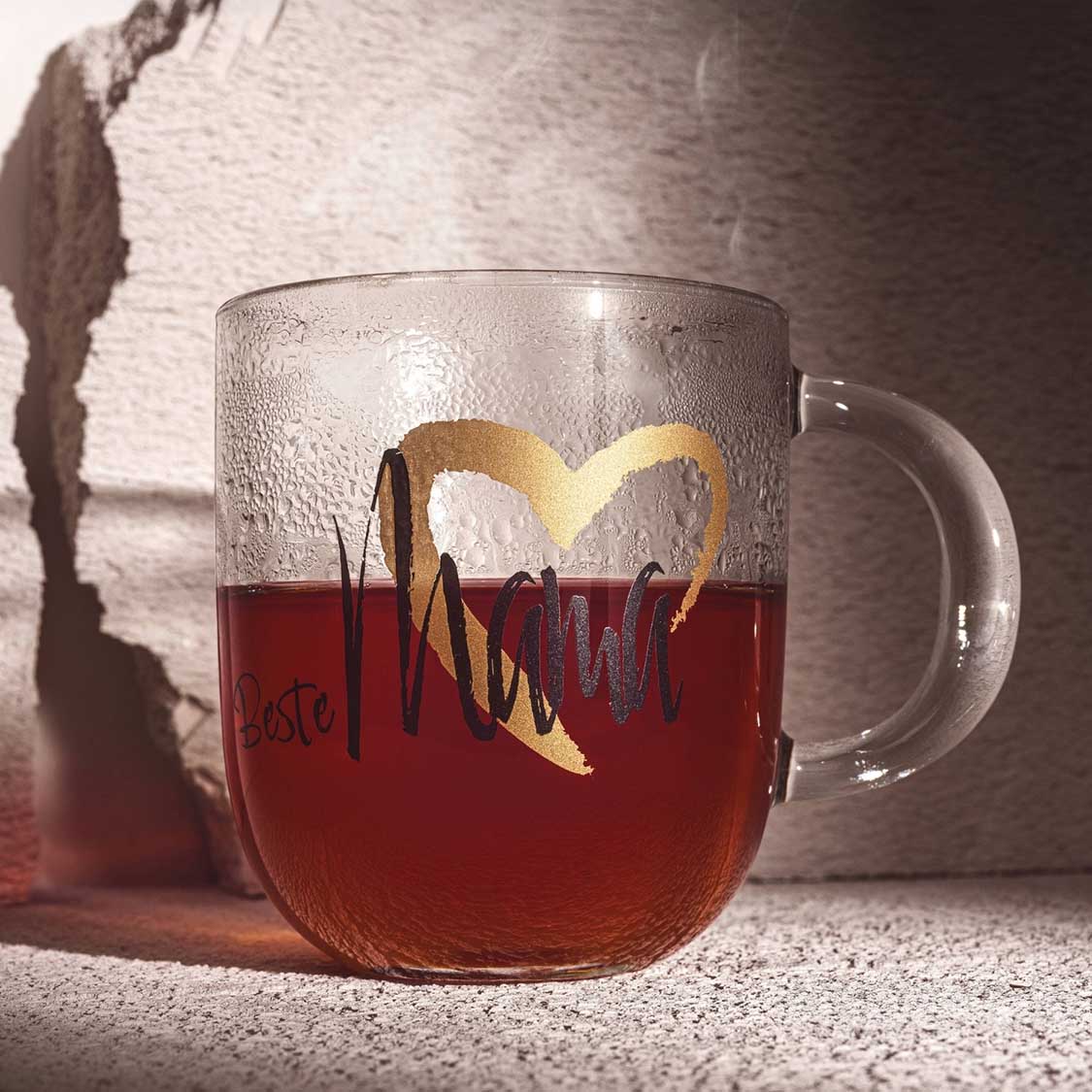 Tasse EMOZIONE mit rotem Tee, Zitronenschale, Schriftzug "Beste Mama" sichtbar