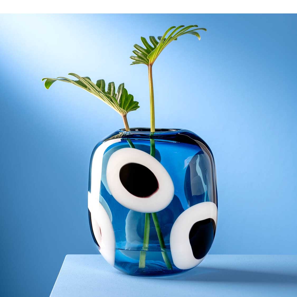 Vase OCCHI BLU mit weißen Augen auf blauem Grund, gefüllt mit Wasser und grünen Pflanzenstängeln