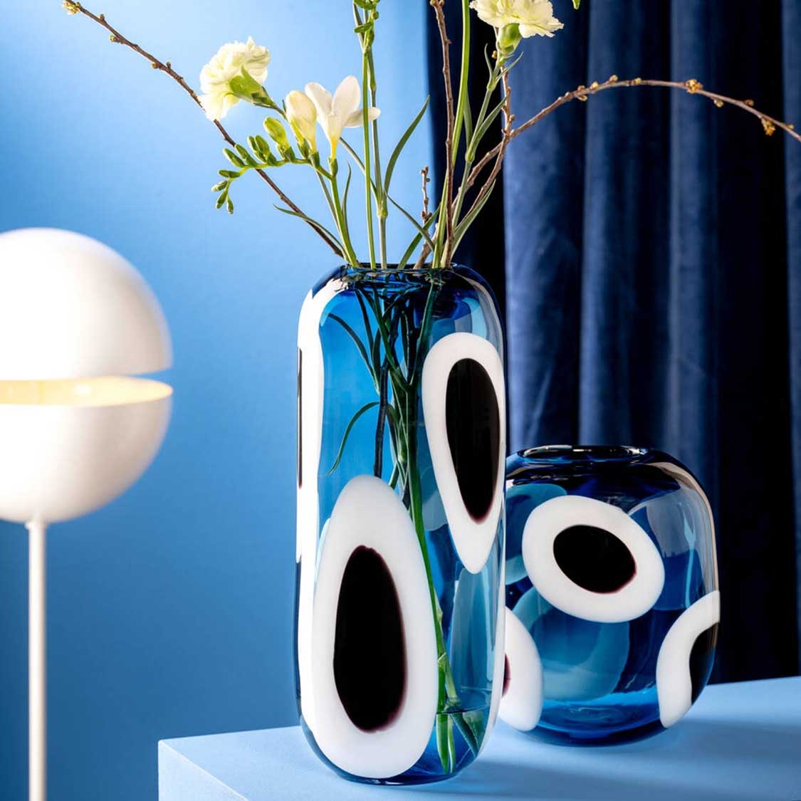 Vase OCCHI BLU mit weißen Augen-Motiven, gefüllt mit gelben Blüten und Zweigen