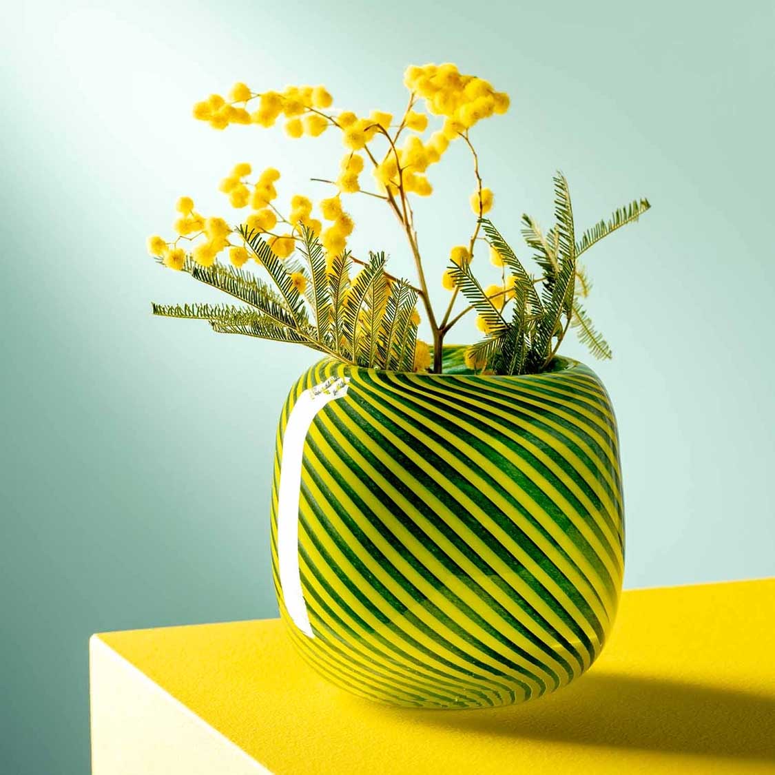 Vase FILO COLORI grün mit gelben Blüten auf gelbem Podest
