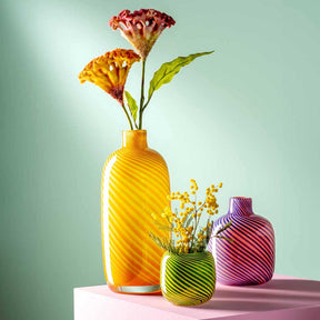 Vase FILO COLORI grün mit gelben und roten Blüten, daneben größere gelbe und lila Vasen